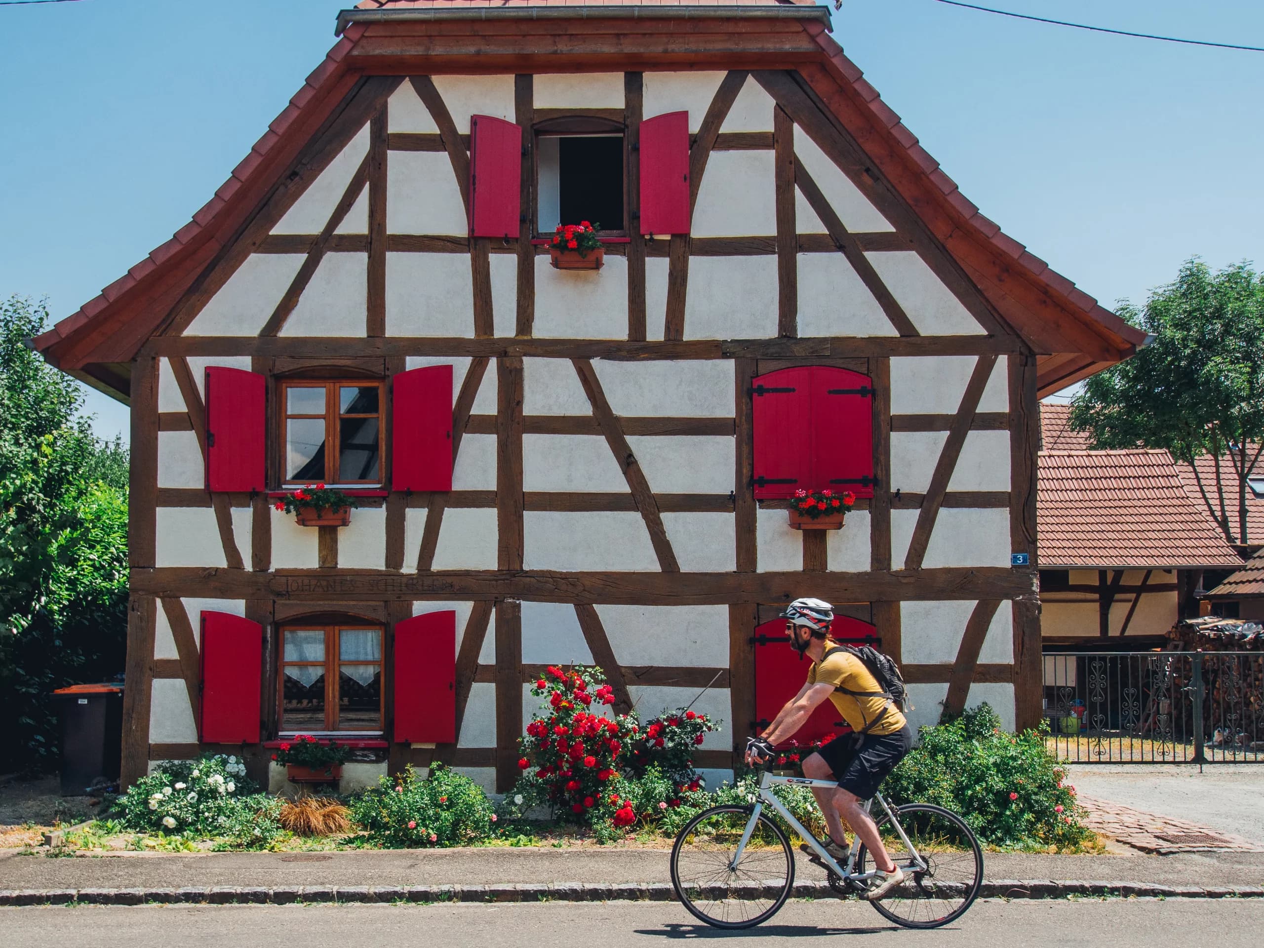 Cycliste devant une maison à colombages en Alsace