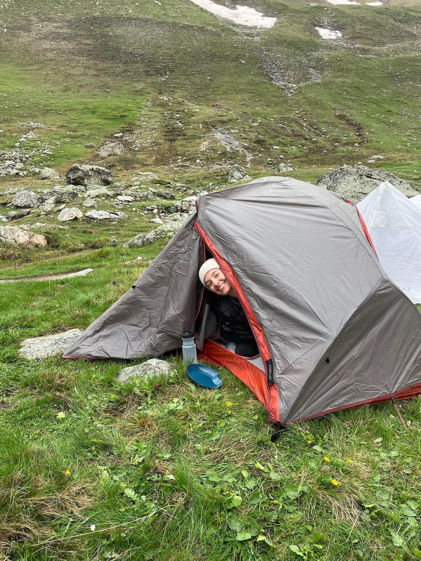 Randonneuse dans sa tente de bivouac installée sur un alpage en montagne